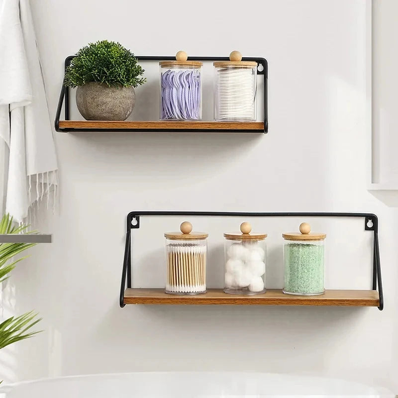 Three clear acrylic apothecary jars with wooden lids filled with lavender, white, and green bath salts displayed on a wooden 