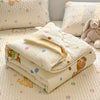 A stack of cream colored lace-trim breathable summer duvet covers and pillows on a quilted surface.