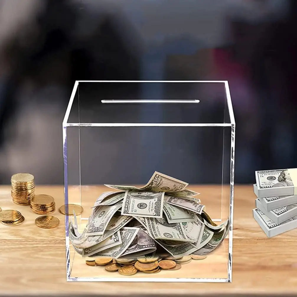 Une tirelire en acrylique transparent remplie de billets et pièces de dollars sur une surface en bois.