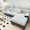 A modern gray sofa with a textured slipcover and dark accents sits in a bright living room.