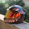 A glossy black and orange retro full-face motorcycle helmet resting on a concrete ledge.