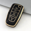 A black and gold TPU car key fob cover case with multiple buttons resting on a white surface.