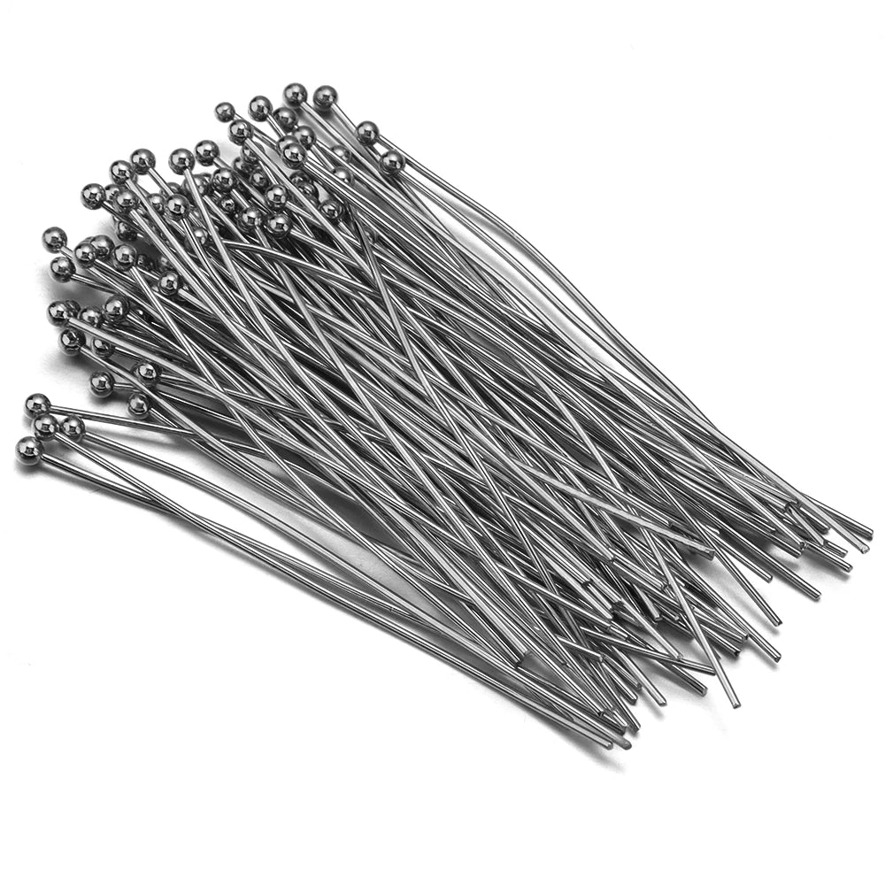 A collection of gold-plated brass ball head pins for jewelry making laid out on a white surface.