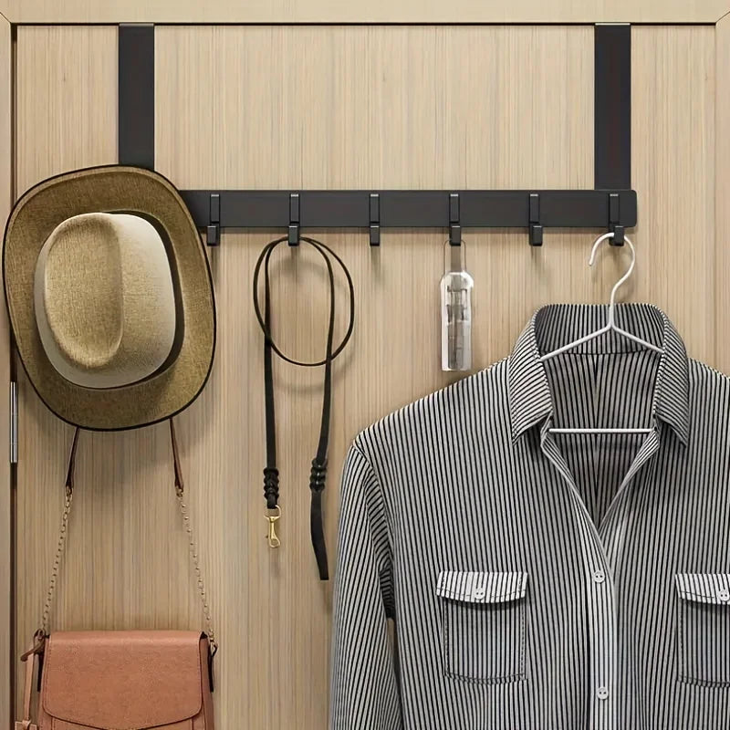 A wooden coat rack with six hooks is mounted on a wall, displaying a hat and a striped shirt.