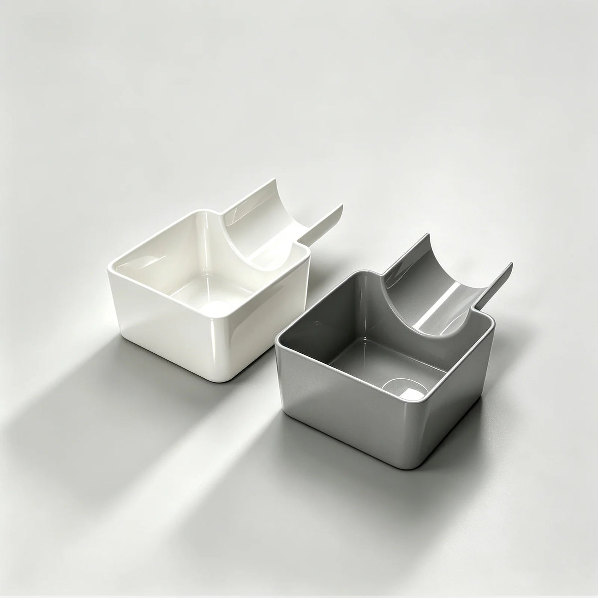 A pair of white and gray washing machine drain funnels with overflow guards and drip pans shown on a light surface.