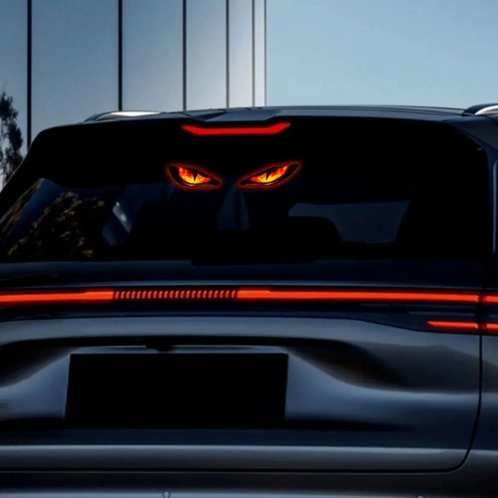 Rückansicht eines dunklen Autos mit leuchtend roten Augen und horizontalen Warnleuchten auf dem Kofferraum.