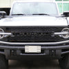 Close-up of a black Ford Bronco grille with a white emblem letter cover installed on the front bumper.