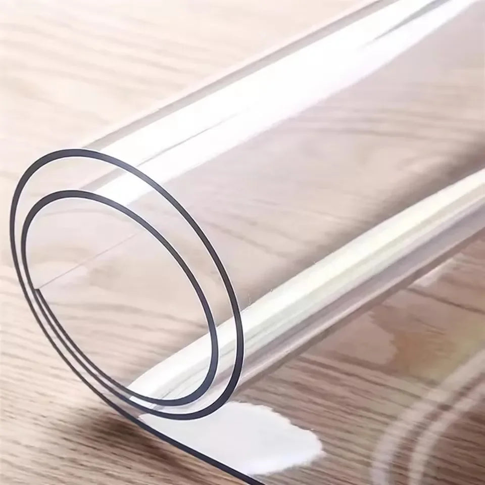 A clear PVC waterproof table protector rolled up on a wooden surface.