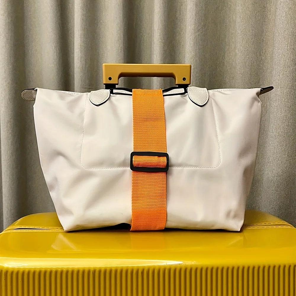 A white reusable elastic luggage strap with an orange strap and a wooden handle resting on a yellow surface.