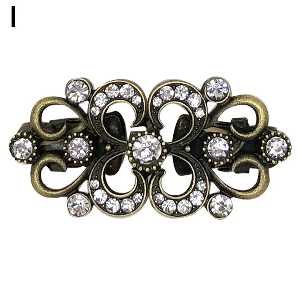 Vintage gold-toned swirl sweater clip featuring clear rhinestones and decorative metalwork