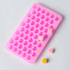 A pink silicone mold with heart-shaped cavities, showing several small pink and yellow heart pieces.
