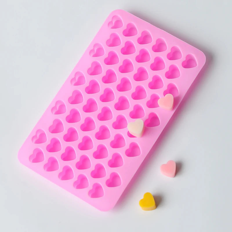A pink silicone mold with heart-shaped cavities, showing several small pink and yellow heart pieces.
