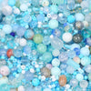 A close-up view of mixed sized glass beads in various shades of blue, white, and purple for jewelry making