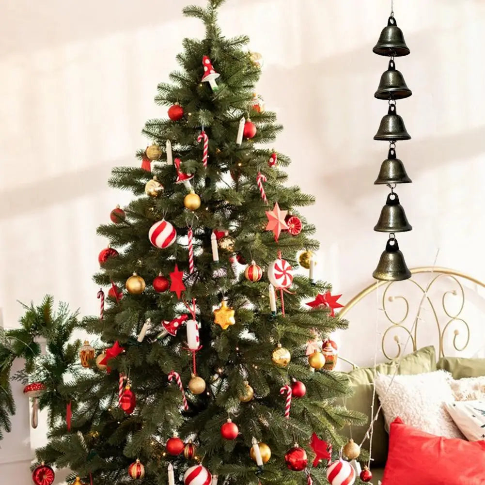 A decorated Christmas tree with ornaments and ribbons, used as a backdrop for vintage iron wind chimes.