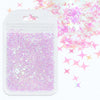 A white plastic pouch filled with iridescent purple and pink holographic star sequins for resin crafts.