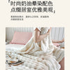 A fluffy white gradient fleece throw blanket draped over a person on a bed.