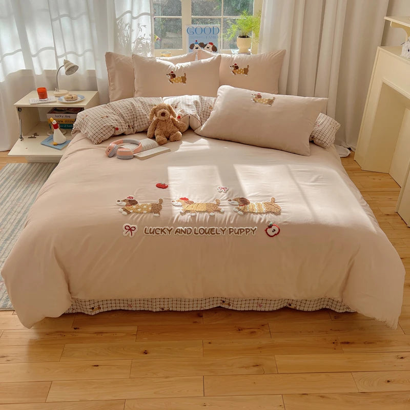 A beige duvet cover set featuring embroidered cartoon puppies and a matching pillow on a bed.