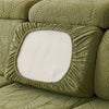 A close-up of a moss green stretch jacquard sofa cover featuring a textured leaf pattern.