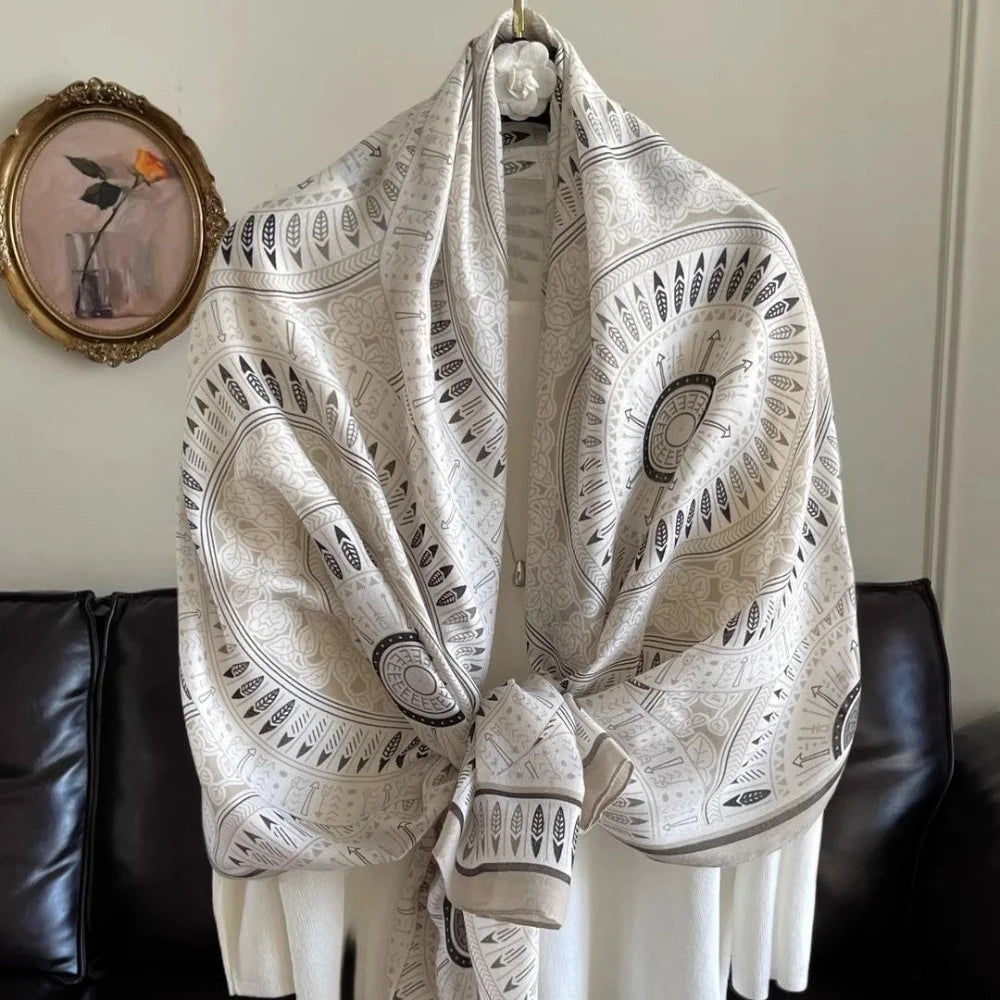 A light gray scarf with intricate black geometric patterns is draped over a white garment.