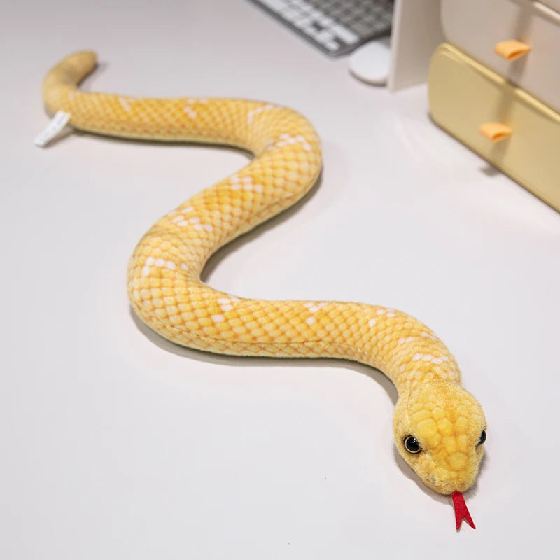 A yellow lifelike snake plush toy resembling an anaconda, coiled on a white surface.