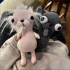 A pink plush chihuahua dog keychain pendant is shown resting on a beige fabric next to a dark gray dog plush.