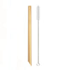 A tall, gold-colored reusable stainless steel drinking straw with a cleaning brush.