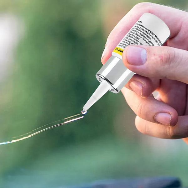 A hand applies a clear resin from a kit to a surface using a glass applicator tip.