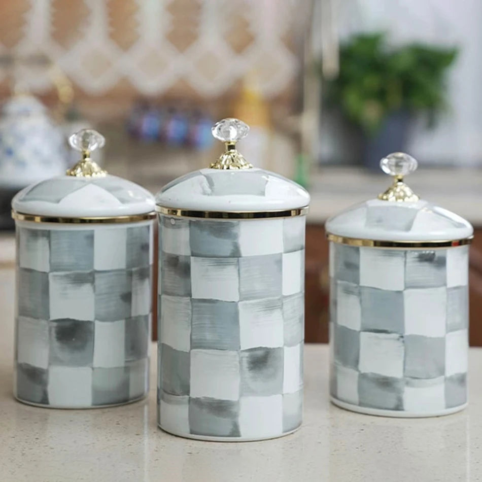 Three white and gray checkerboard porcelain storage jars with gold lids