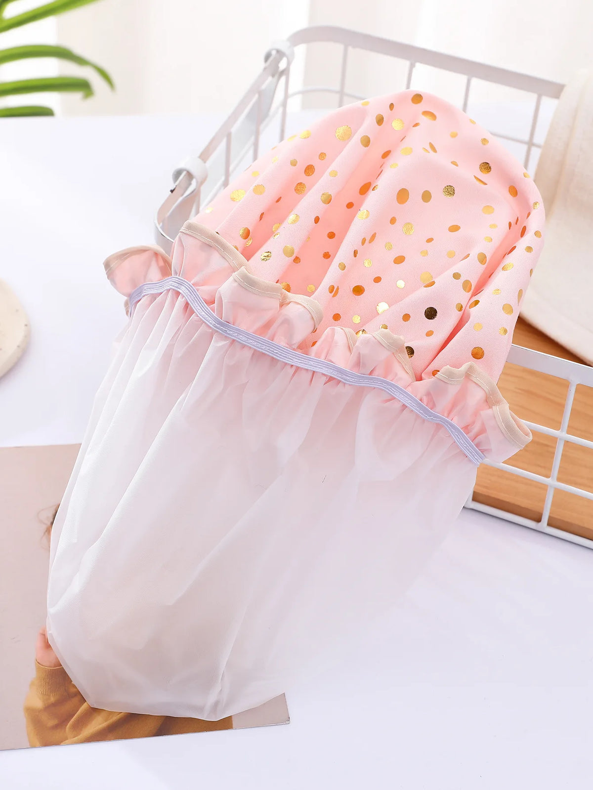 A reusable elastic shower cap for women in pink and white with gold polka dots, shown on a white surface.