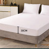 A white fitted mattress protector with an elastic edge is shown on a bed, highlighting its 30cm height design.