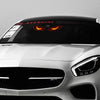 A close-up of a car's front, featuring a black visor with glowing orange demon eyes and a silver grille.