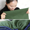 A close-up of a dark green heavy-duty canvas laundry bag with a blue drawstring closure.
