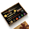 A wooden box contains a vintage calligraphy fountain pen set with wax seal stamp kit and various accessories.