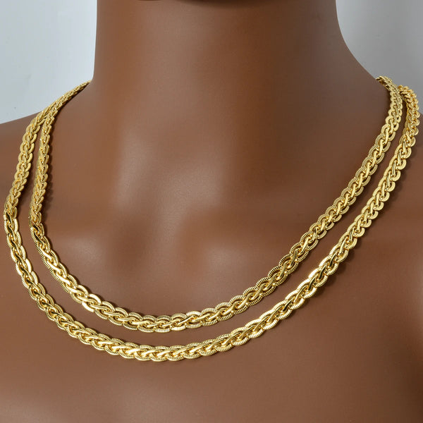 A close-up of a gold-plated Cuban link chain necklace displayed on a neck form.