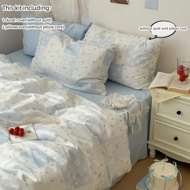 A set of blue floral duvet cover and two pillowcases with a white patterned blanket on a bed.