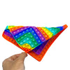 A hand holds a colorful multiplication practice math game board with various colored tiles.