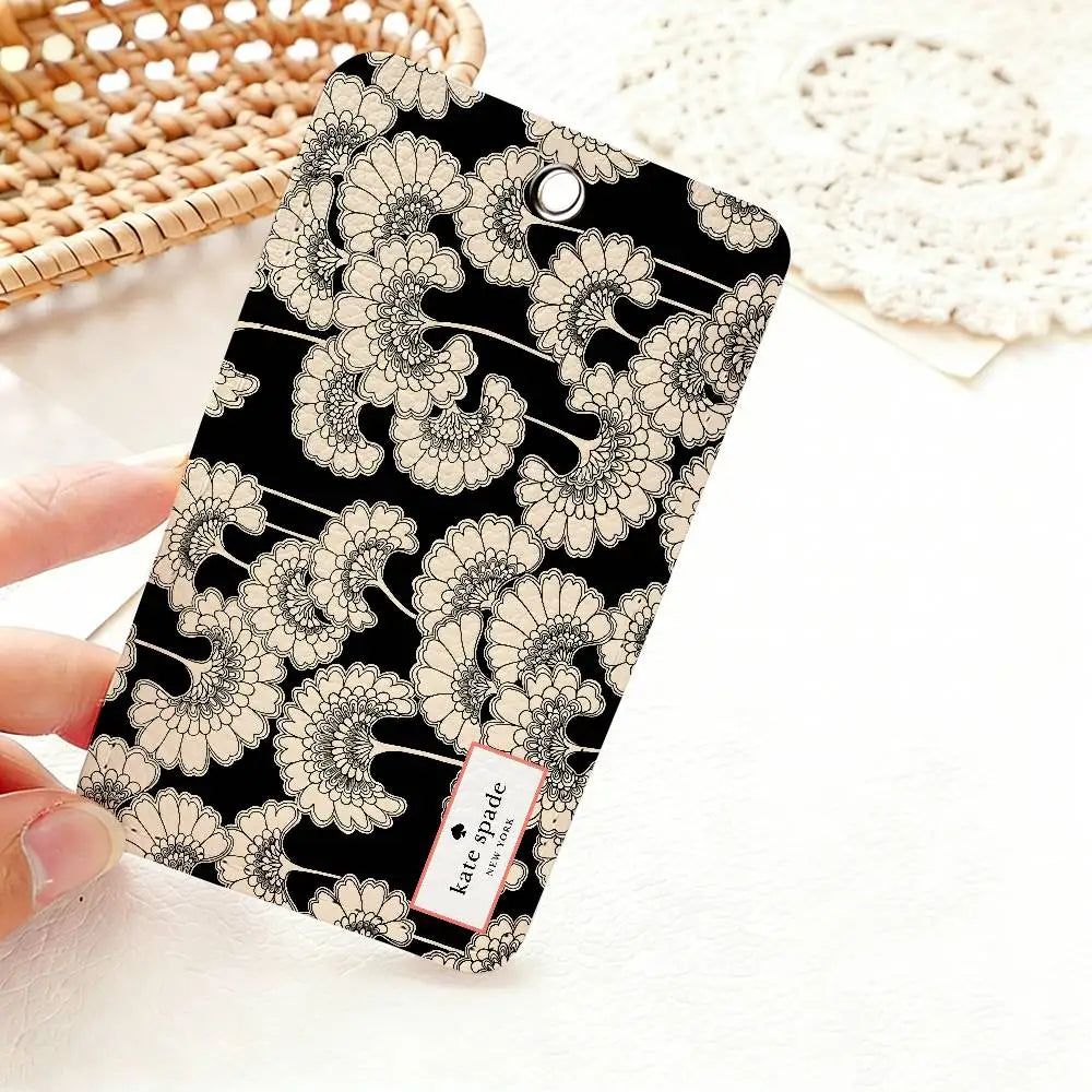 A black card holder featuring a delicate floral pattern in beige and white is held against a white background.