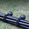 Black elastic tent tie-down ropes with plastic buckles lying on green grass