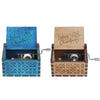 A hand-cranked wooden music box with a blue lid and natural wood casing featuring engraved Christmas text.