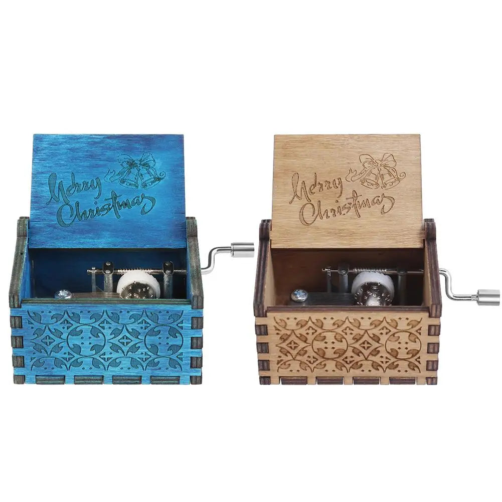 A hand-cranked wooden music box with a blue lid and natural wood casing featuring engraved Christmas text.