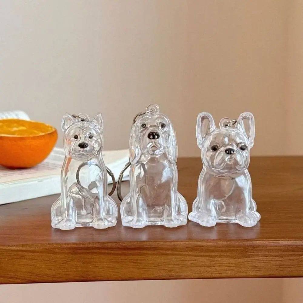 Three clear silicone dog-shaped keepsakes or pendants displayed on a wooden surface.
