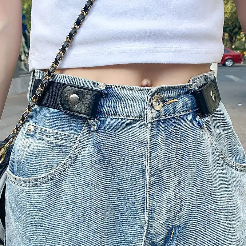 A close-up of a light wash denim skirt with a black leather belt and chain strap.