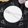 Silver heart-shaped spring hook keychains displayed on a white plate against a dark fabric background.
