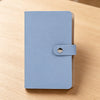 A light blue 100-slot cash organizer binder with a snap closure resting on a wooden surface.