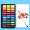 A professional watercolor paint set with a black metal case showing various colors arranged in a grid.