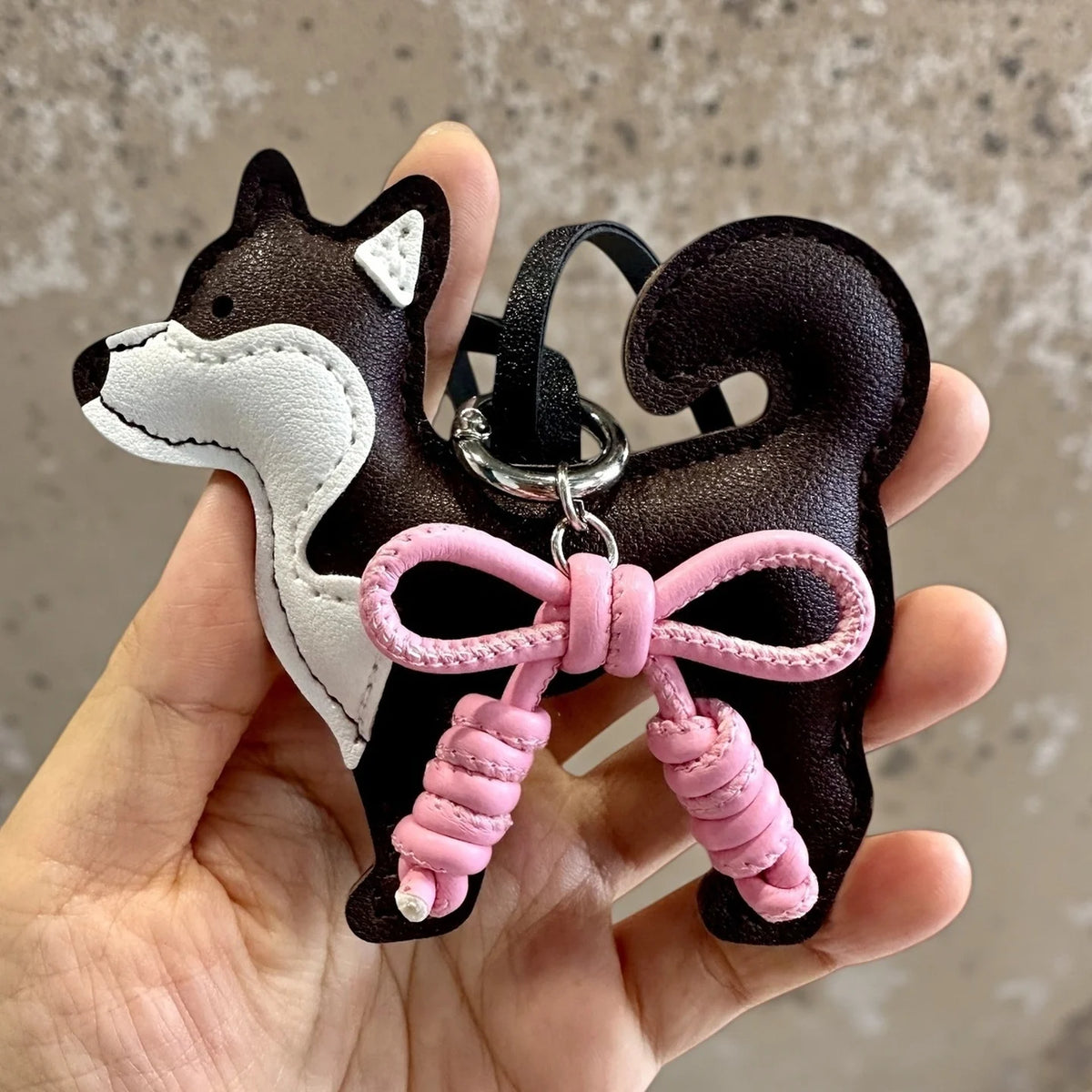 A black and white Shiba Inu PU leather bag charm featuring a braided pink bow.