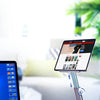 A rotating aluminum tablet stand is shown on a wooden desk, demonstrating telescopic adjustment for improved sitting habits.