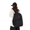 A person wearing a black baseball cap and a beige top is carrying an urban nylon backpack for everyday commute.