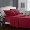 A bedroom featuring a red bedding set with a white headboard, dark wood floor, and bedside lamps.