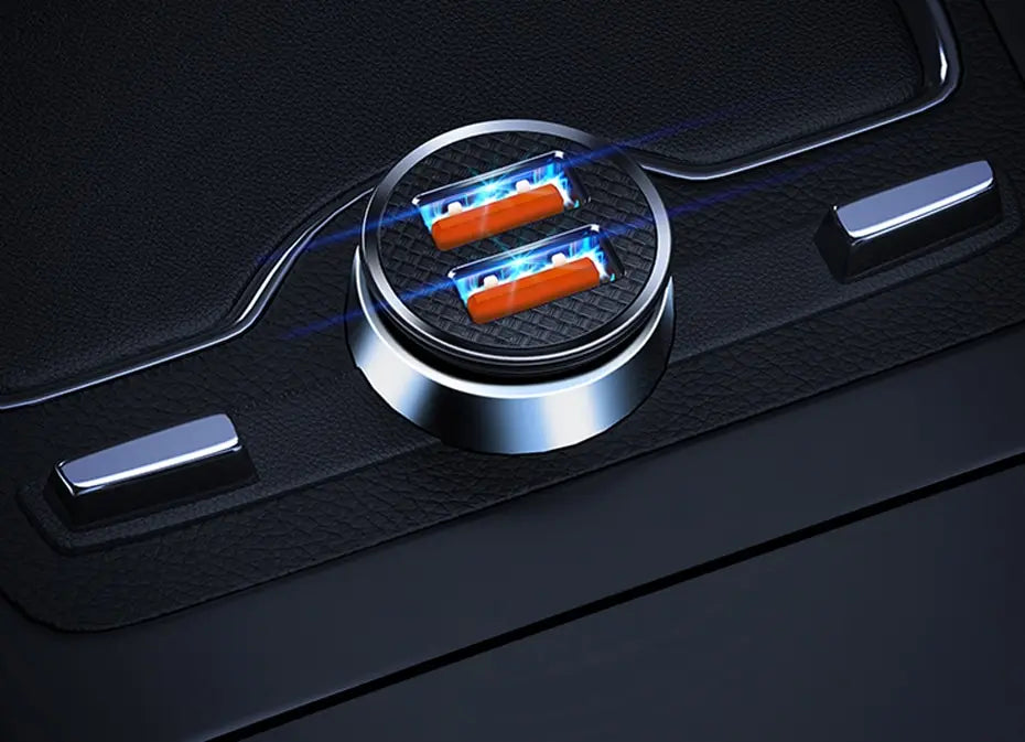 A close-up view of a silver USB-C car charger with two orange ports, illuminated by blue light on a black surface.